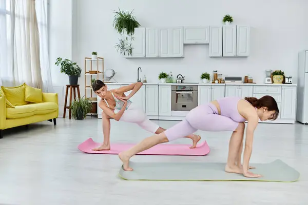 Two young women in athletic wear practice yoga together in a modern apartment. — Stock Photo