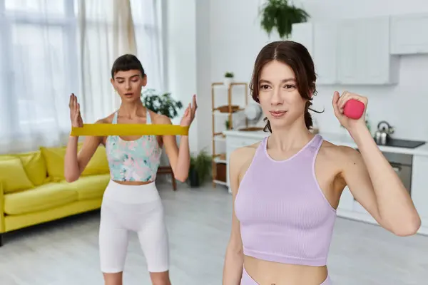 Two women in sportswear exercise together in a modern apartment. — Stock Photo