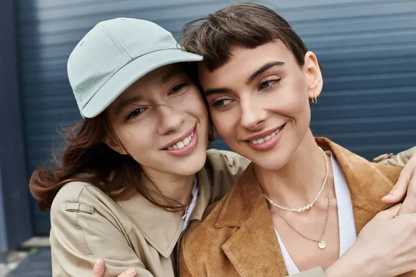 Zwei Frauen in stylischen Outfits verbringen einen glücklichen Moment im Freien, während die Stadtkulisse ihrer Umarmung Energie verleiht — Stockfoto