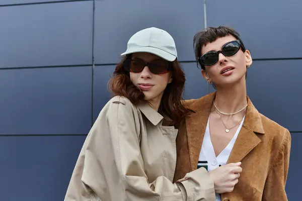 A stylish lesbian couple poses confidently against a blue wall. — Stock Photo