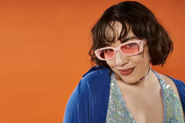 A woman in a vibrant blue outfit and pink sunglasses looks confidently toward the viewer. — Stock Photo