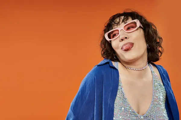 A woman in a blue shirt and sparkly top sticks her tongue out playfully. — Stock Photo