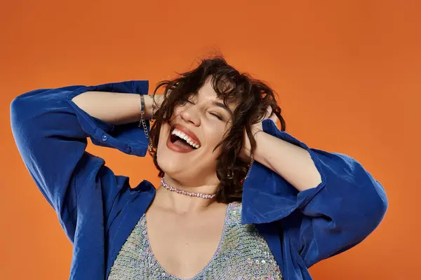 Woman in blue jacket laughs against orange background — Stock Photo