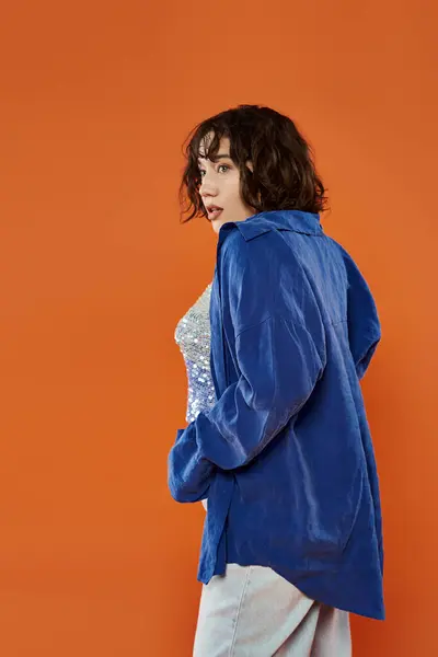Mulher de camisa azul contra fundo laranja olha para longe da câmera — Fotografia de Stock