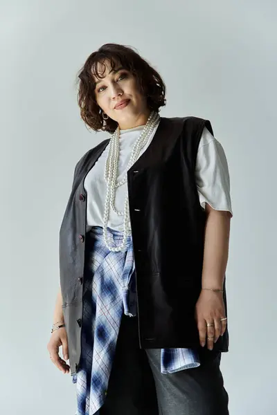 A woman in a black vest and a plaid shirt looks confidently at the camera. — Stock Photo