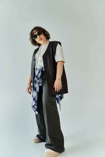A woman wearing a black vest and wide-legged pants poses against a white backdrop. — Stock Photo