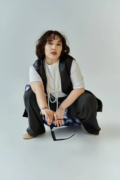 A woman in black pants and a white shirt sits with a thoughtful expression. — Stock Photo