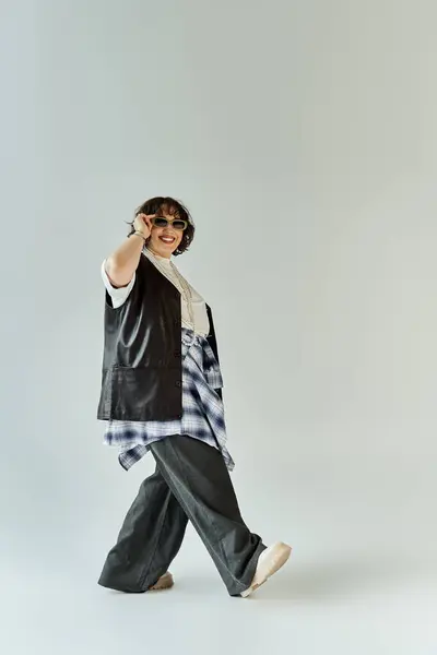 A woman in a black vest and wide-leg pants walks with a confident stride. — Stock Photo