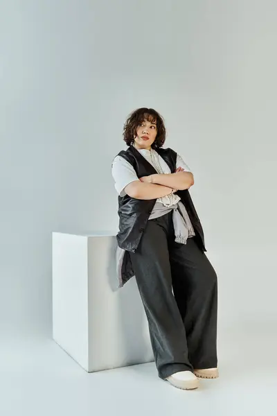 Una mujer en un traje colorido se apoya en un cubo blanco, mirando reflexivo. — Stock Photo