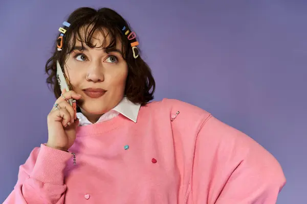 Uma jovem mulher com uma camisola rosa fala ao telefone, perdido em pensamento. — Fotografia de Stock