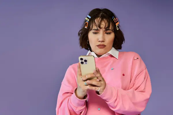 A woman in a pink sweater uses her phone while looking down thoughtfully. — Stock Photo