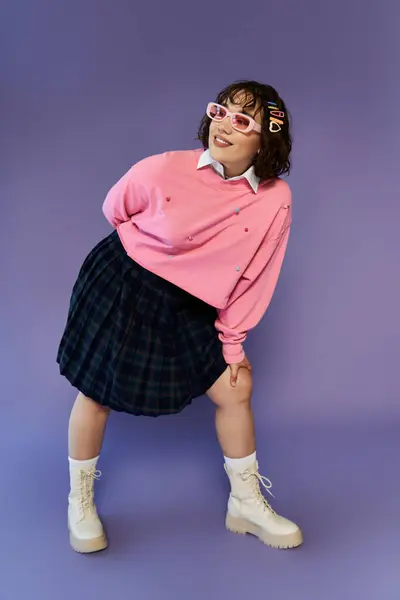 Una joven con un atuendo vibrante, posando juguetonamente sobre un telón de fondo púrpura. - foto de stock