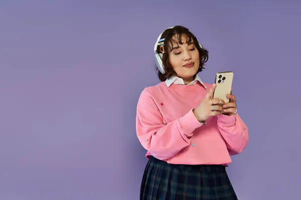 Woman wearing headphones, using a smartphone, with a purple backdrop. — Stock Photo