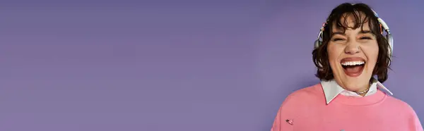 A woman wearing headphones smiles broadly against a purple backdrop. — Stock Photo