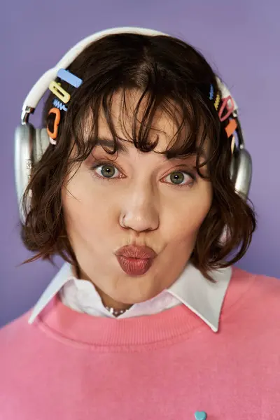 A woman wearing headphones and a pink sweater makes a playful face. — Stock Photo