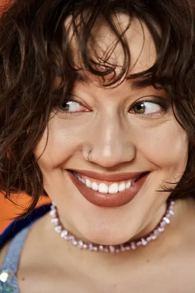 A woman with dark curly hair smiles brightly, wearing a colorful necklace. — Stock Photo