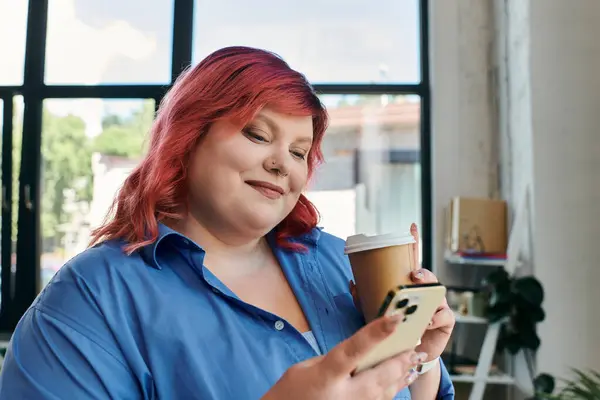 Бизнесменка plus-size с розовыми волосами держит чашку кофе и проверяет свой телефон. — стоковое фото