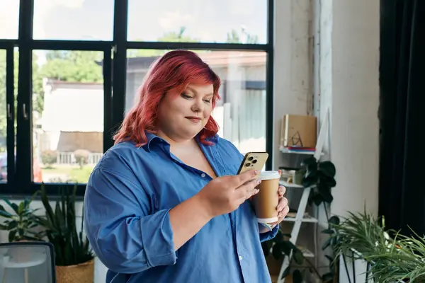 A plus size businesswoman with vibrant pink hair checks her phone while holding a cup of coffee. — Stock Photo
