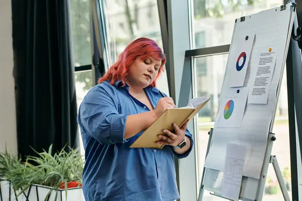 Женщина plus size в синей рубашке делает заметки во время встречи. — стоковое фото