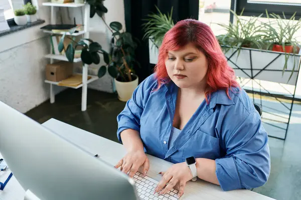 Бизнесменка plus-size с ярко-розовыми волосами на компьютере в своем современном офисе. — стоковое фото