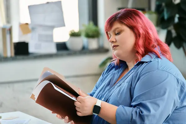 A plus size woman with pink hair reviews documents while sitting in an office. — Stock Photo