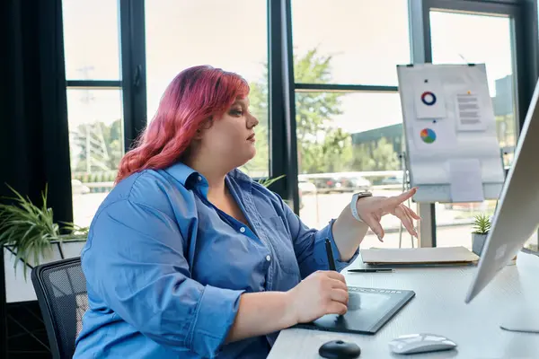 Una donna plus size con i capelli rosa lavora al suo computer. — Foto stock