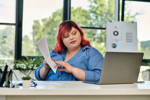 A plus size woman reviews a document at her desk in a modern office. — Stock Photo
