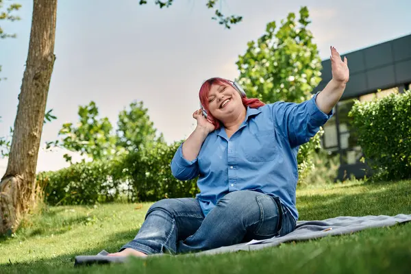 A plus size woman in a blue shirt and jeans enjoys the music on a sunny day. — Stock Photo