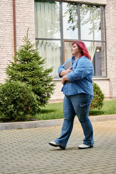 A plus size woman with bright red hair walks confidently on a paved path. — Stock Photo