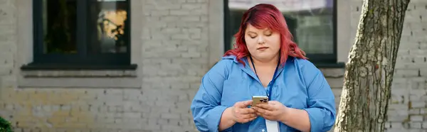 Una mujer de talla grande comprueba su teléfono mientras camina por la calle. - foto de stock