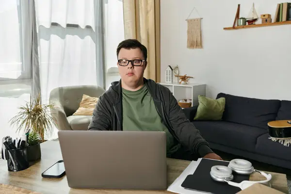 A young man with Down syndrome engages in an online learning session in his cozy home. — Stock Photo