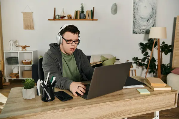 A young man with Down syndrome engages with his laptop at home. — Stock Photo