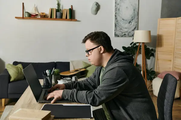 A young man with Down syndrome focused on tasks at his home workspace in the evening. — Stock Photo