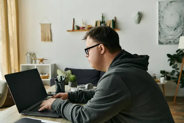 Focused individual working on a laptop in a comfortable home environment. — Stock Photo