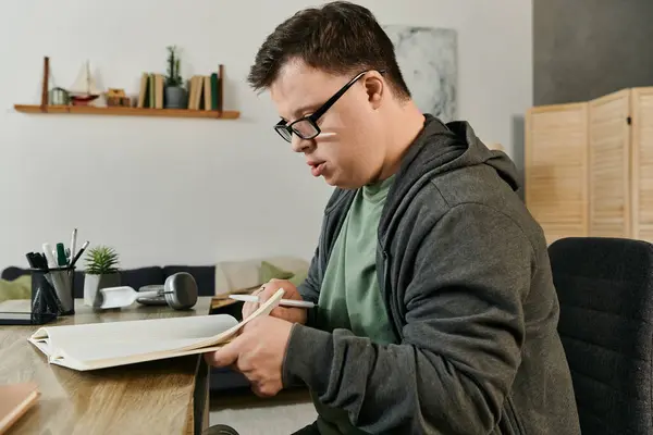 Un giovane con la sindrome di Down si concentra sulla sua scrittura, circondato da un ambiente domestico caldo e invitante. — Foto stock