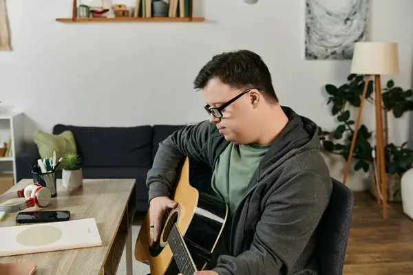 A man with Down syndrome practices guitar, surrounded by a warm and inviting home atmosphere. — Stock Photo