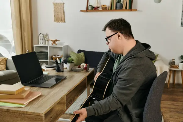 Un joven con síndrome de Down disfruta rasguñando su guitarra en un espacio cálido y acogedor. - foto de stock