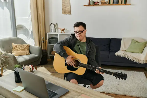 Strumming a guitar, a man with Down syndrome shares music in his comfortable home environment. — Stock Photo