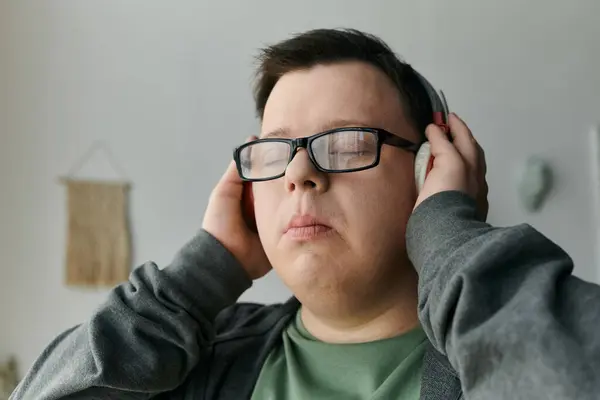 A young man with Down syndrome cherishes a peaceful moment while listening to music. — Stock Photo