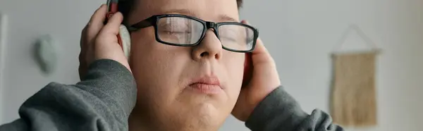 A young man with Down syndrome listens intently to music while relaxing at home. — Stock Photo