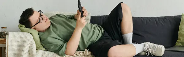 A young man with Down syndrome enjoys leisure time lounging on the couch. — Stock Photo