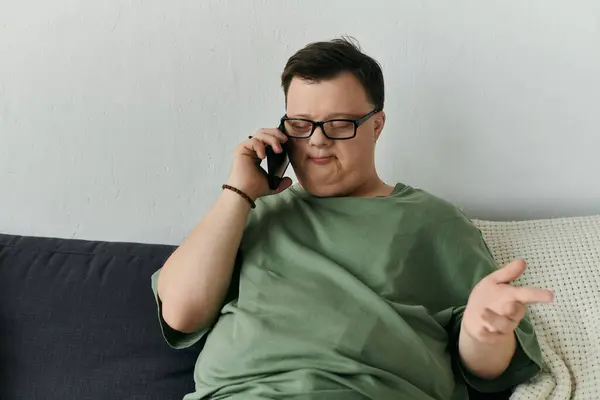 A man with Down syndrome engages in a heartfelt phone call from his cozy living room. — Stock Photo
