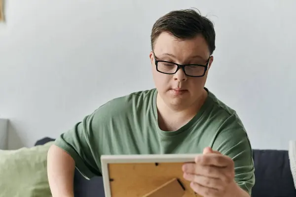 A young man with Down syndrome creates art while seated comfortably in his living space. — Stock Photo
