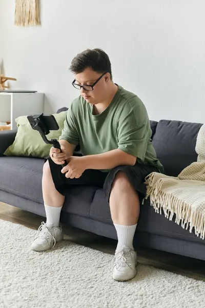 A man with Down syndrome sits thoughtfully on a couch at home. — Stock Photo
