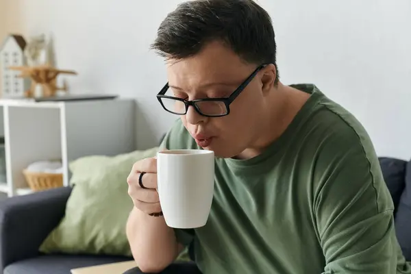 Чоловік з синдромом Дауна насолоджується теплим напоєм у затишній домашній обстановці. — стокове фото