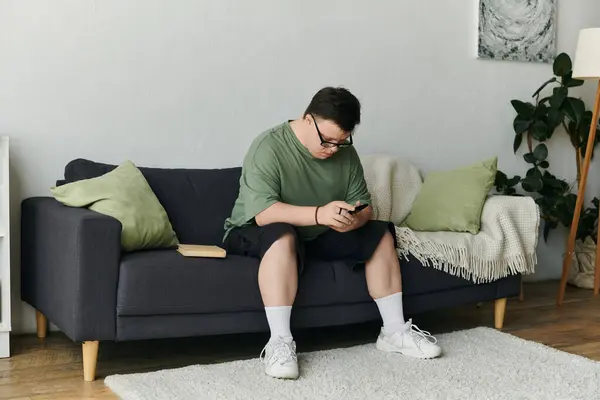 A young man with Down syndrome enjoys his free time while sitting comfortably at home. — Stock Photo