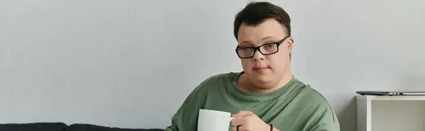 A man with Down syndrome enjoys a quiet moment at home with his favorite beverage. — Stock Photo