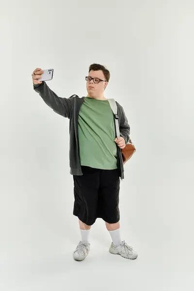 A young man with Down syndrome captures a selfie while smiling in his cozy living space. — Stock Photo