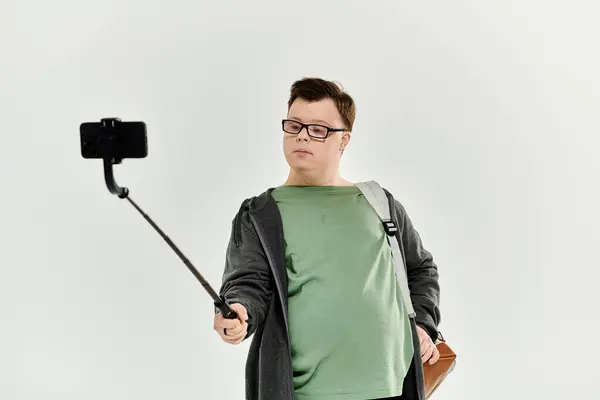 Ein fröhlicher junger Mann mit Down-Syndrom fängt einen freudigen Moment mit seinem Selfie-Stick ein. — Stockfoto