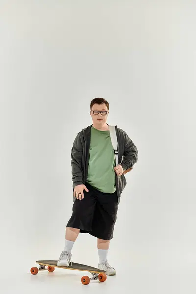 A young man with Down syndrome enjoys skateboarding indoors in a relaxed outfit. — Stock Photo